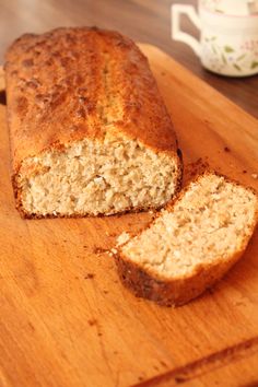 a loaf of bread sitting on top of a wooden cutting board next to a cup