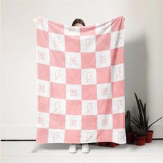 a woman holding up a pink and white checkered blanket with lightning bolt on it