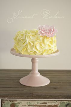 a cake with yellow and pink frosting sitting on top of a wooden table