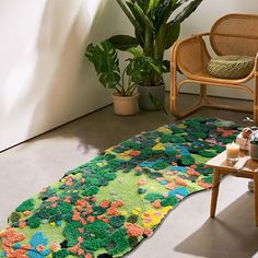 a living room with a rug on the floor next to a chair and potted plant