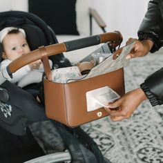 a baby in a stroller being held by a person with a purse on it