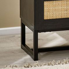 a wooden table with a rattan drawer on top and a white rug underneath it