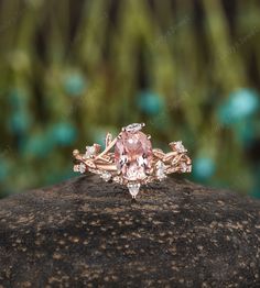 a pink diamond ring sitting on top of a rock