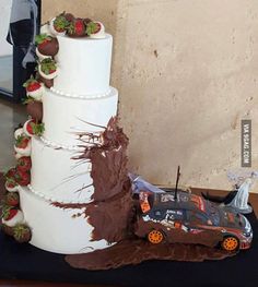 a wedding cake with strawberries on top and a car in the middle next to it