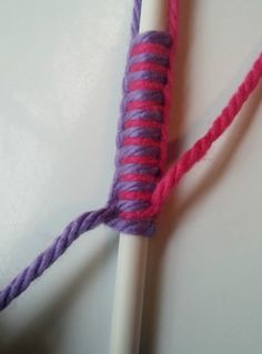 a purple and pink yarn is on top of a white crochet hook