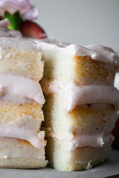 two pieces of cake with frosting and strawberries in the background