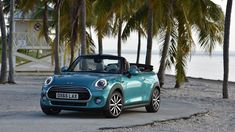 a small blue car is parked on the side of the road near some palm trees