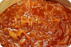 a wooden spoon is stirring chili sauce in a pot with tortilla chips on the side