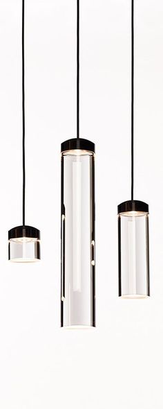 three glass pendants hanging from black cords and one light fixture is suspended above the other