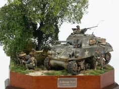 an army tank is on display with other figurines and trees in the background