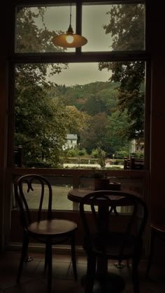 two chairs and a table in front of a window with a view of trees outside