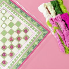 two pieces of fabric are laying next to each other on a pink surface with green and white squares