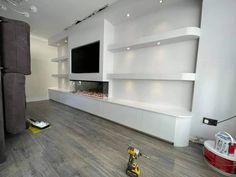 a room that has some shelves and a tv on the wall, with tools in front of it