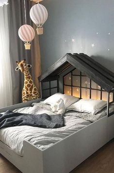 a child's bed with a house made out of cardboard and stuffed giraffe