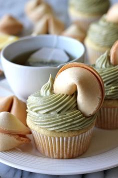 cupcakes with green icing and some other dessert items in the foreground