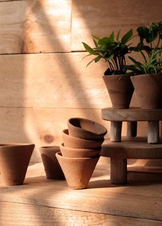 a stack of clay pots sitting on top of a wooden table next to a potted plant