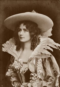 an old black and white photo of a woman wearing a hat with feathers on it