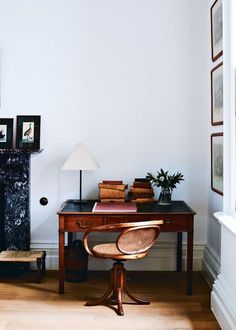 a room with a desk, chair and pictures on the wall above it is also a fireplace