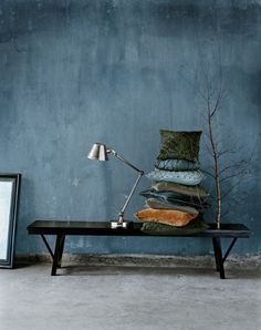 a room with blue walls and a black coffee table topped with a pile of pillows