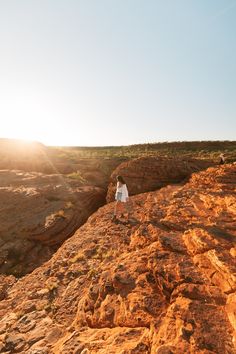 a woman standing on top of a rocky cliff