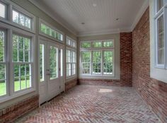 an empty room with brick floors and large windows on either side of the door,