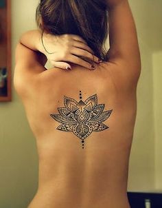 the back of a woman's body with a lotus tattoo on her left side