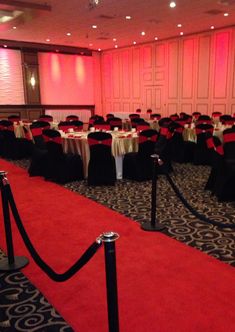 a banquet room set up with red and black linens, white tablecloths and chairs