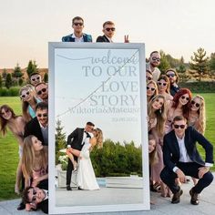 a group of people posing for a photo in front of a large sign that says welcome to our love story