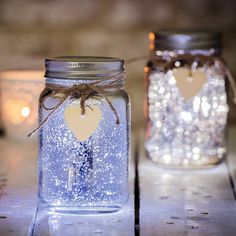 two mason jars with lights in the background and a heart shaped tag attached to them