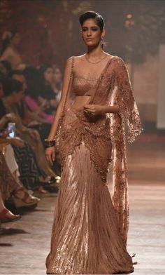 a model walks down the runway in a brown gown