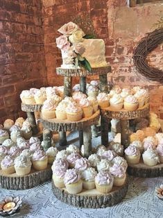 a table topped with cupcakes and cakes covered in frosted icing on top of each other