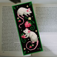 a cross stitch bookmark with an image of a white mouse on it's side