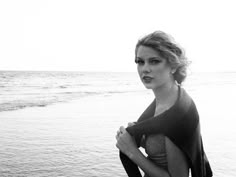 a woman standing on the beach next to the ocean