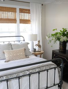 a bed with white sheets and pillows in a bedroom next to a black chest of drawers