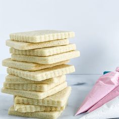 a stack of shortbread crackers next to an origami pink paper airplane