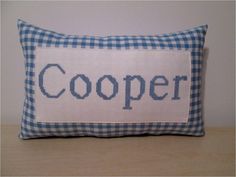 a blue and white pillow with the word cooper on it's front side