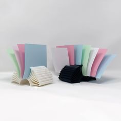 several different colored papers stacked on top of each other in front of a white background