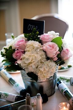 flowers in a bucket on a table with candles