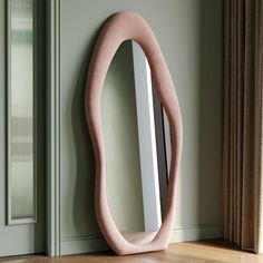 a mirror sitting on top of a wooden floor next to a door