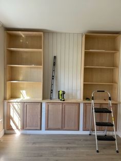 a ladder is in the middle of a room with wooden cabinets and shelvings