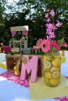 a mason jar filled with lemons sitting on top of a table next to a wooden letter