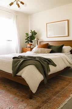 a bedroom with a bed, rugs and plants in the corner on the floor