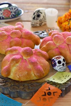 some breads with pink frosting on them sitting on a table next to a skull