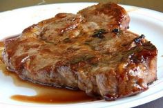 two steaks on a white plate covered in sauce