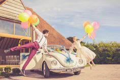 a man and woman standing on the back of a car with balloons in front of them