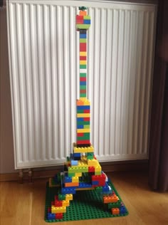 a tall tower made out of legos sitting on top of a wooden floor next to a radiator