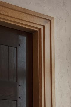 an open wooden door in a room with white walls and wood trimming on the wall