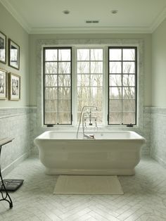 a white bath tub sitting next to two windows