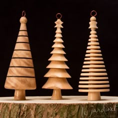 three wooden christmas trees sitting on top of a tree stump