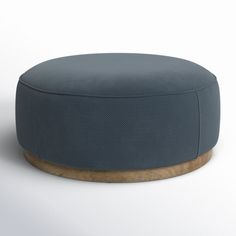 a blue round ottoman sitting on top of a white floor next to a wooden base